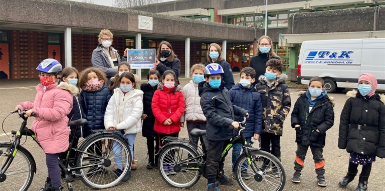 Bezirksbürgermeisterin Hanna Rosenbaum (hinten 2.v.l.) übergab den symbolischen Bildungsscheck für neue Fahrräder an Maren Krebs (hinten l.) vom Förderverein der Diesterweg-Grundschule, Daniela Köchling und Schulleiterin Corinna Holland (hinten r.) und Kinder der Schule.