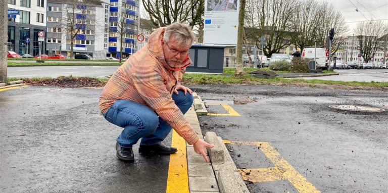 Jens Kaulisch zeigt den Höhenunterschied, der zwischen Radsteinen und der Oberkannte der Parkstoppsteine am Radwall bleibt.