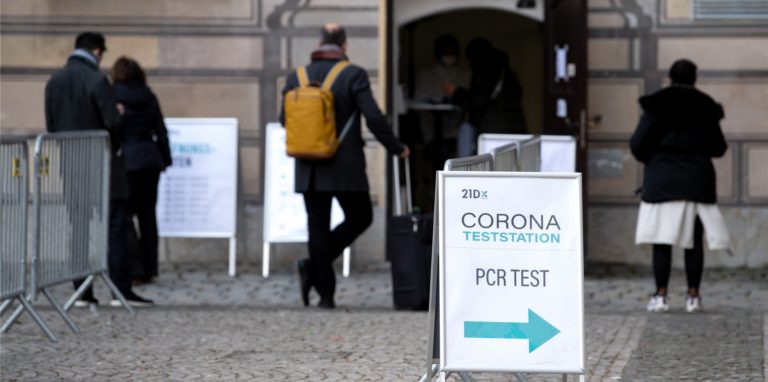 Menschen stehen vor einer Corona-Teststation in der Innenstadt in einer Warteschlange. Die Virusvariante Omikron treibt die Corona-Zahlen in Deutschland weiter nach oben.