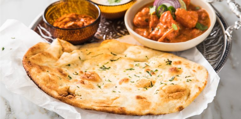 Der Naan-Fladen kann zu Chicken Tikka Masala, Gemüse-Raita und Mixed Pickles aufgerupft werden.