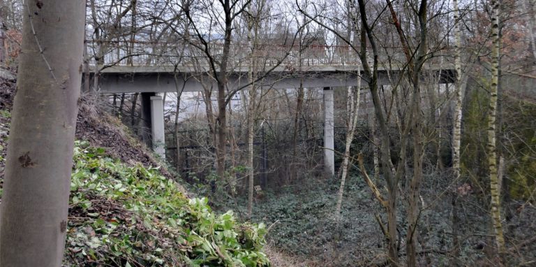 Durch diesen Einschnitt fuhren die Züge unter der Brücke hindurch und durch ein Tor in der Werksmauer auf das Gelände der Münzfabrik.