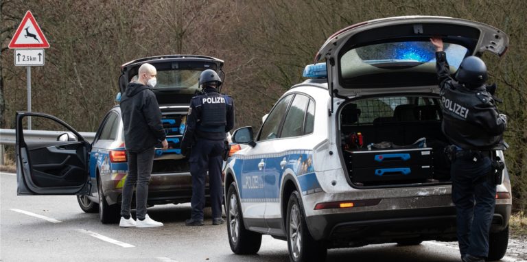 Polizeibeamte stehen an einer Absperrung an der Kreisstraße 22, rund einen Kilometer von dem Tatort entfernt, an dem zwei Polizeibeamte durch Schüsse getötet wurden. Die tödlichen Schüsse fielen nach Polizei-Angaben bei einer routinemäßigen Verkehrskontrolle.
