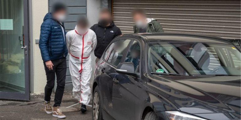 Polizisten bringen einen der Tatverdächtigen (im weißen Overall) nach dem Haftprüfungstermin am Landgericht Kaiserslautern aus dem Justizgebäude.