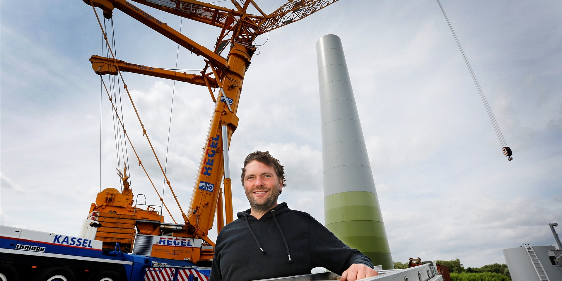 Nils Henter steht im Jahr 2022 in der Nähe der Hansastraße in Bergkamen vor einem in Bau befindlichen Windrad.