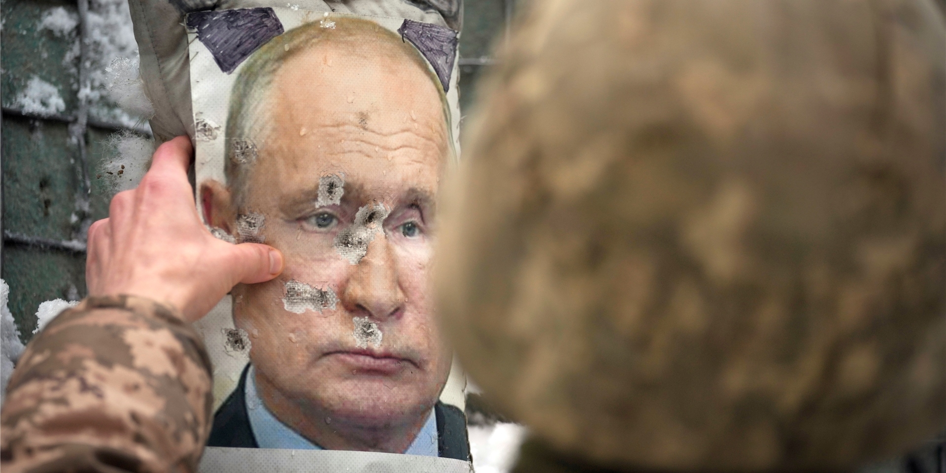 Ukraine, Luhansk: Ein ukrainischer Soldat justiert ein von Kugeln durchlöchertes Bild des russischen Präsidenten Putin.