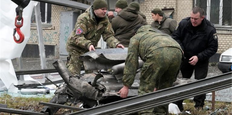 Arbeiter räumen die Trümmer einer Rakete auf einen Lastwagen, nach einem russischen Beschuss.