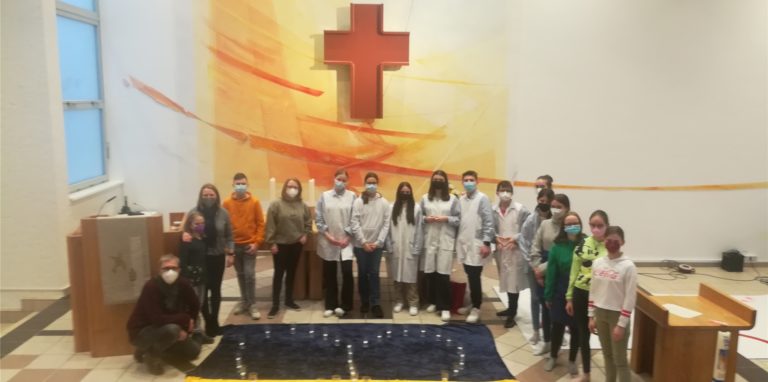 Die Kinder des „Jugend-Stübchen“ stehen vor einer großen gemalten Ukraine-Flagge mit einem Herz aus Kerzen.