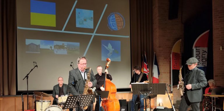 Zum Konzert der Band „Well Connected“ hatte der Städtepartnerschaftsverein Selm Szenen aus den drei Partnerstädten, aber auch die ukrainische Flagge und eine Friedenstaube auf die Leinwand werfen lassen.