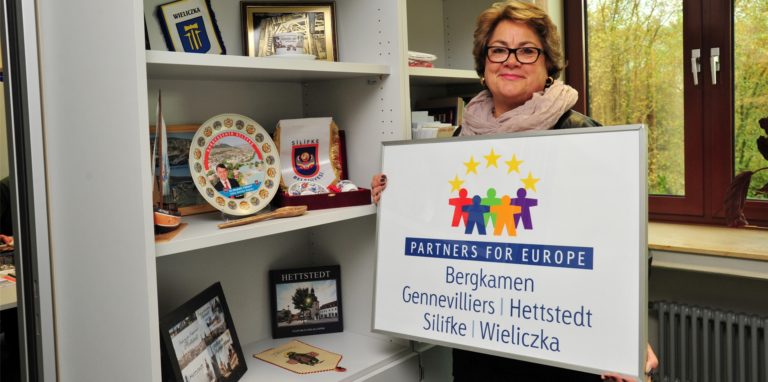 Bergkamens langjährige Partnerschaftsbeauftragte Angelika Joormann-Luft mit dem Schild der Partnerstädte Bergkamen, Gennevilliers, Hettstedt, Silifke und Wieliczka.