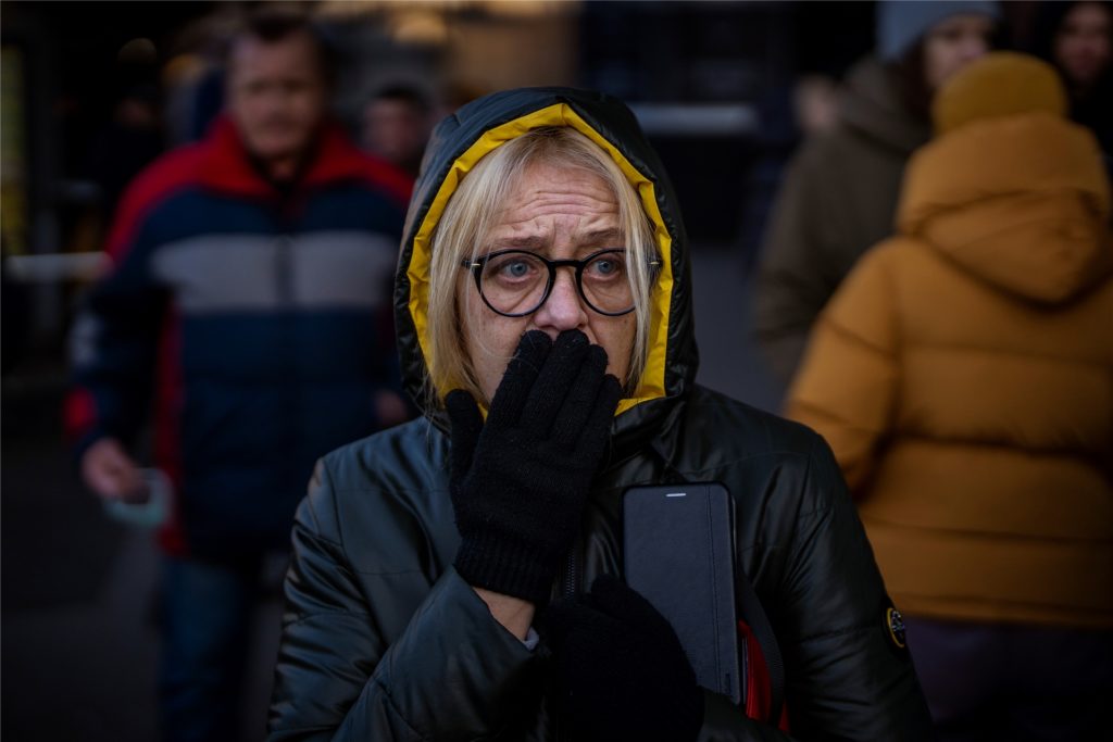 Eine Frau reagiert vor einem Supermarkt im Zentrum der ukrainischen Hauptstadt auf Sirenen, die neue Angriffe ankündigen. In Kiew und anderen ukrainischen Städten sollen nach dem Angriff durch Russland zentrale Verteilungspunkte für Lebensmittel eingerichtet werden
