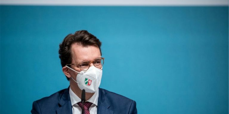 Hendrik Wüst (CDU), Ministerpräsident von Nordrhein-Westfalen, sitzt auf dem Podium.