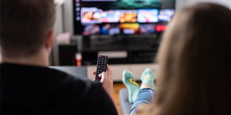 Ein Paar sitzt vor dem Fernseher und guckt Netflix, der Mann hält die Fernbedienung. (Symbolbild)