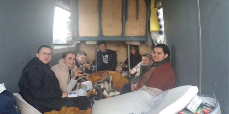 Geflüchtete Ukrainer sitzen in einem Anhänger
