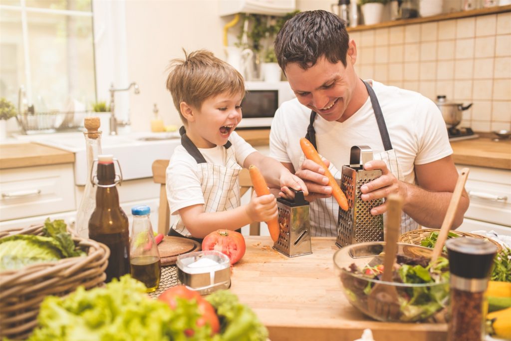 Ein junger Vater schneidet mit seinem Sohn in der Küche Gemüse. Ein junger Vater schneidet mit seinem Sohn in der Küche Gemüse.