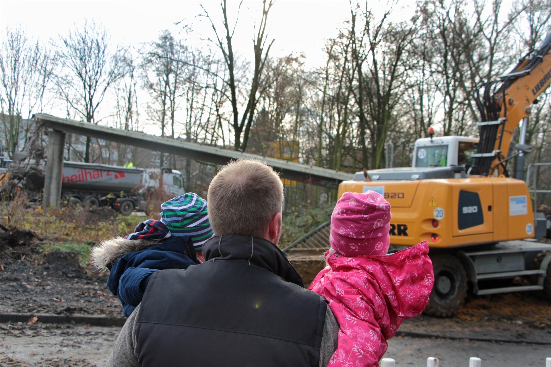 Vater und zwei kleine Kinder beobachten einen Bagger.