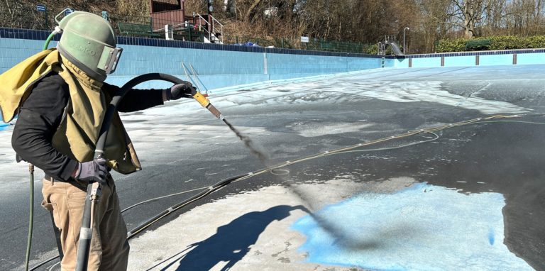 Die Sandstrahler sind im Freibad Dellwig: Die alte mehrschichtige Farbe muss von einer Spezialfirma entfernt werden, bevor eine neue besondere Farbe für Schwimmbäder aufgetragen werden kann.