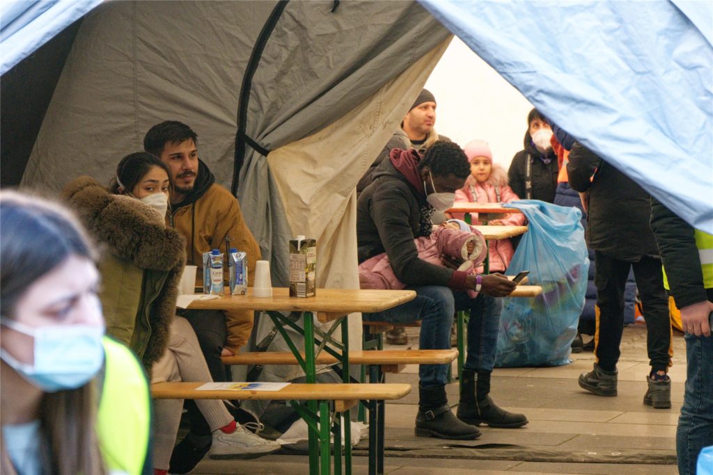 Geflüchtete sitzen in einem Zelt der Anlaufstelle am Hauptbahnhof. Die Stadt Köln hat am Hauptbahnhof aus Zelten eine Anlaufstelle für Geflüchtete aus der Ukraine eingerichtet.