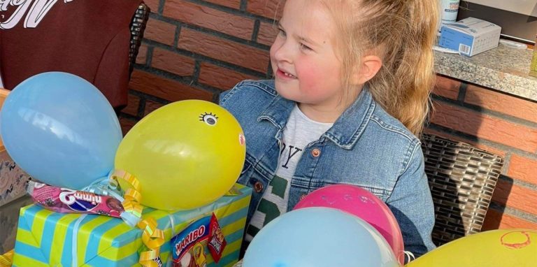 Milana sitzt am Tisch, vor ihr liegen Geschenke