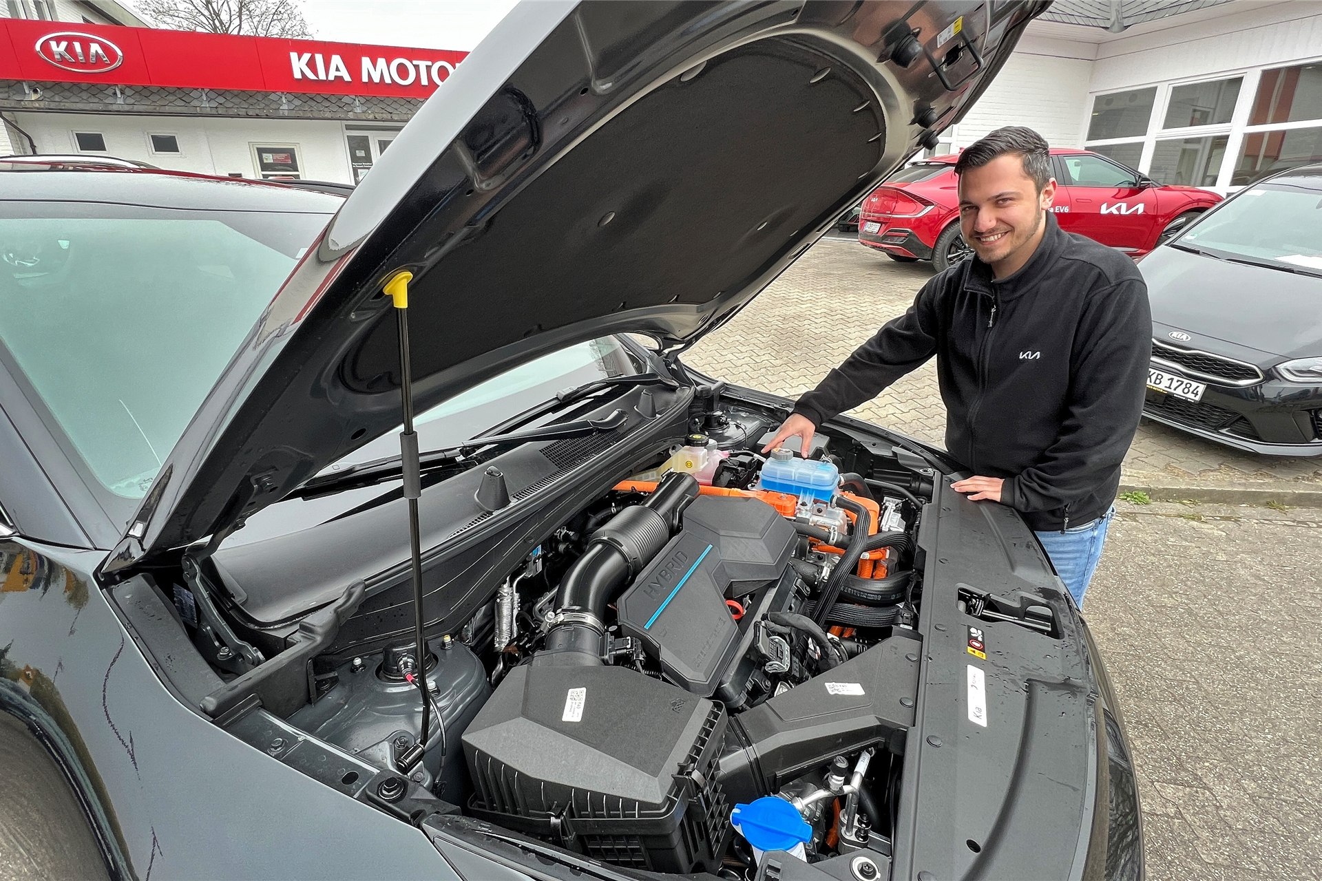 Automobilkaufmann Etienne Brandt zeigt den Elektromotor unter der Motorhaube des neuen Kia Sportage. Autos mit reinem Elektro- oder Hybridantrieb könnten in der Energiekrise noch an Bedeutung gewinnen.