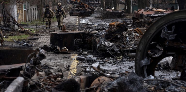 Zwei ukrainische Soldaten gehen auf einer Straße, die übersät ist mit zerstörten russischen Militärfahrzeugen. In der ukrainischen Stadt Butscha, 25 Kilometer nordwestlich der Hauptstadt Kiew, bietet sich nach dem Rückzug der russischen Armee ein Bild des Grauens.
