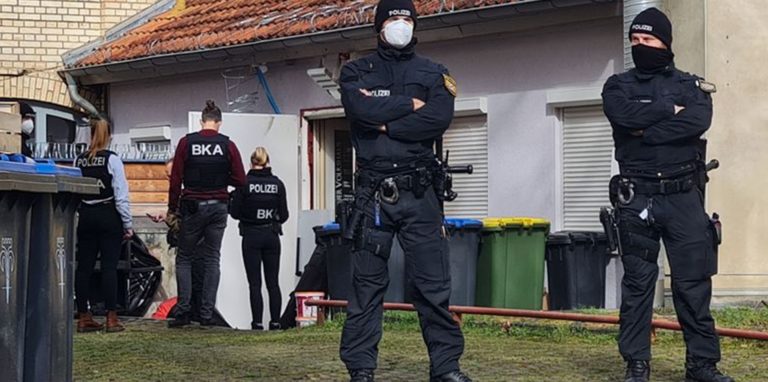 Polizisten vor einem Hintereingang eines Gebäudes in Eisenach, das sie durchsuchen.