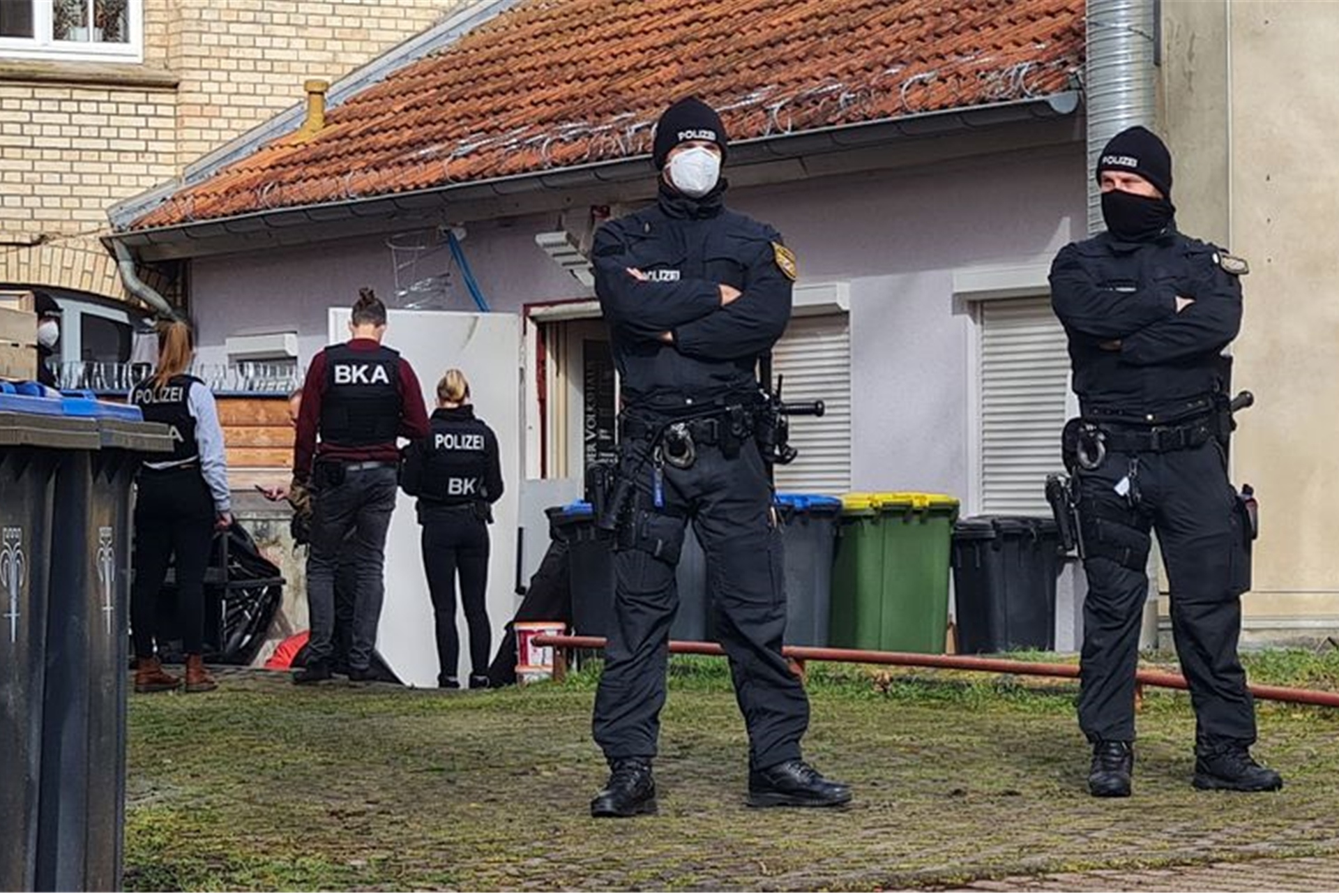 Polizisten vor einem Hintereingang eines Gebäudes in Eisenach, das sie durchsuchen.