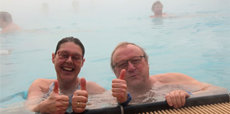 Zwei Menschen sind im Wasser und zeigen mit dem Daumen nach oben