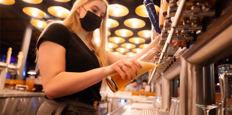 Eine Barkeeperin zapft ein Bier.