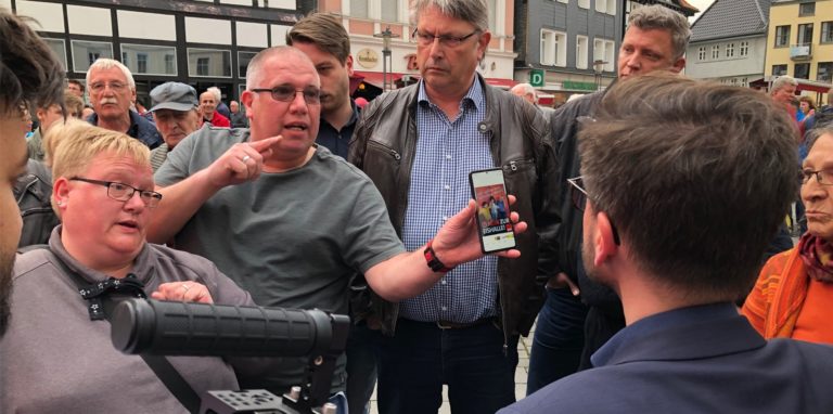 Ein Eishallen-Befürworter konfrontieren SPD-Spitzenkandidat Thomas Kutschaty mit einem SPD-Plakat zum bevorstehenden Bürgerentscheid. Die Kritik an der Haltung seiner Partei in Unna traf den Landespolitiker offenbar unvorbereitet.