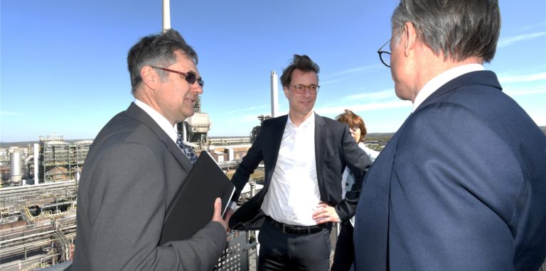 NRW-Ministerpräsident Hendrik Wüst (M.) auf dem Balkon des Hochhauses im Chemiepark Marl im Gespräch mit Marls Standortleiter Bernhard Vendt.