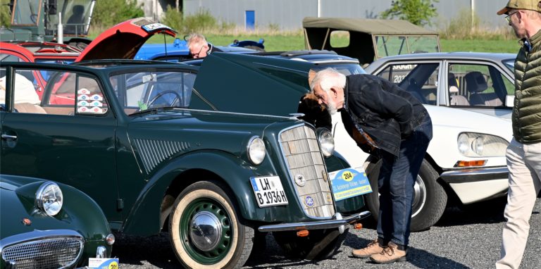 Männer gucken sich Oldtimer an.