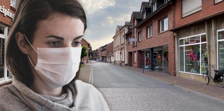 Eine Frau mit Mundschutz steht in einer Straße.