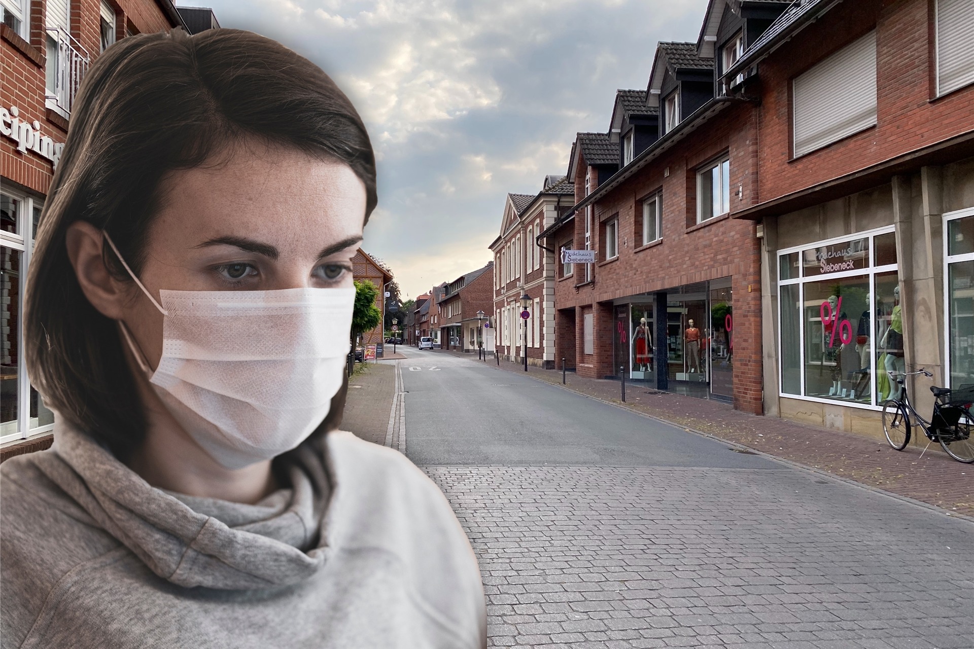 Eine Frau mit Mundschutz steht in einer Straße.