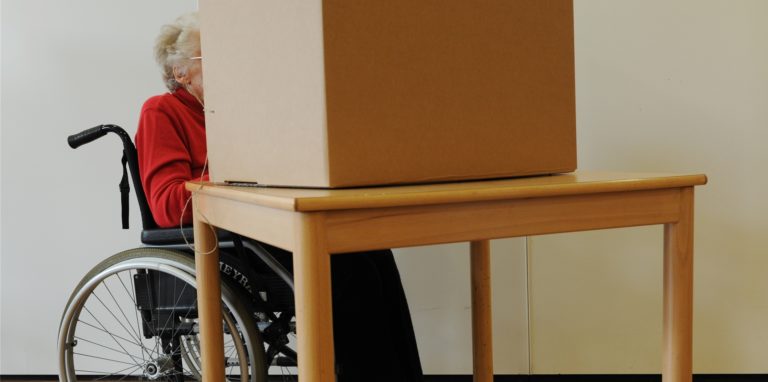 Eine Wählerin im Rollstuhl gibt in einem Wahllokal ihre Stimme ab. Nicht alle Wahllokale in Schwerte sind offiziell barrierefrei.