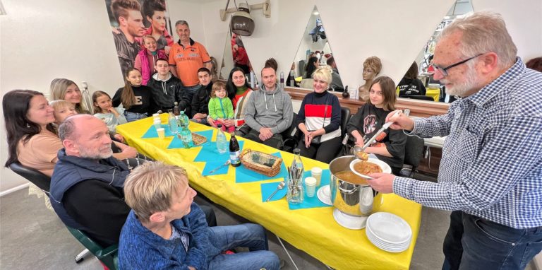 Richard Grünewald (re.) lud Geflüchtete in seinen Friseursalon ein. Christian Knospe (hinten, orangenes Shirt) wünscht sich finanzielle Erleichterungen für Geflüchtete.