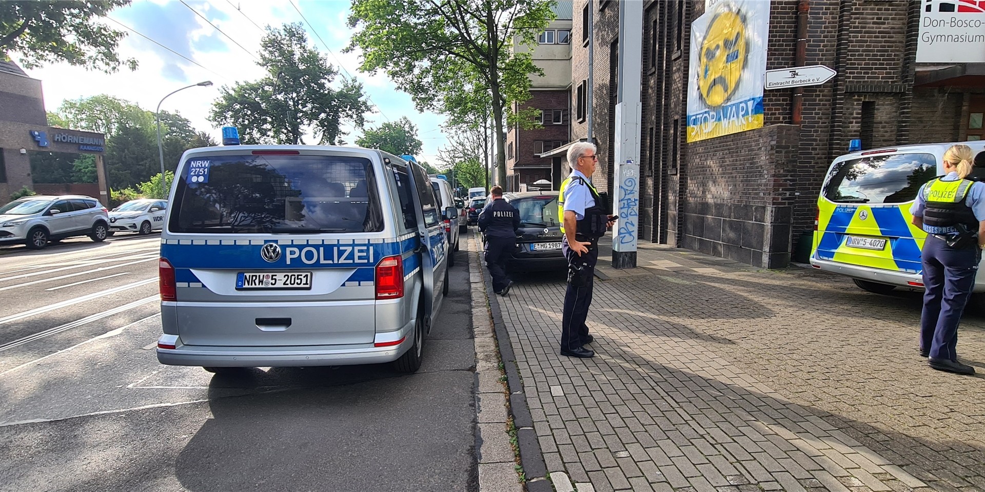 Polizei steht vor dem Don-Bosco-Gymnasium. In Essen ist die Polizei an zwei Schulen in größerem Umfang im Einsatz. Derzeit laufe ein größerer Polizeieinsatz am Don-Bosco-Gymnasium in Essen-Borbeck, schrieb die Polizei auf Twitter. Kurz darauf berichtete sie, der Polizeieinsatz betreffe auch die Realschule am Schloss Borbeck.