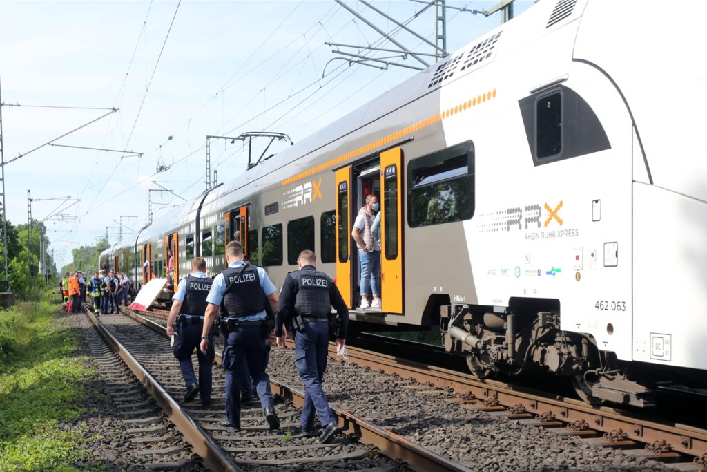Polizisten gehen an einer Regionalbahn entlang. Polizisten gehen an einer Regionalbahn entlang.