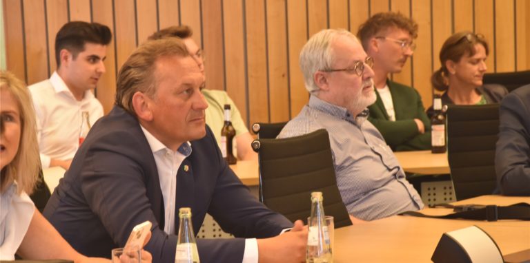 Männer sitzen auf Stühlen und gucken