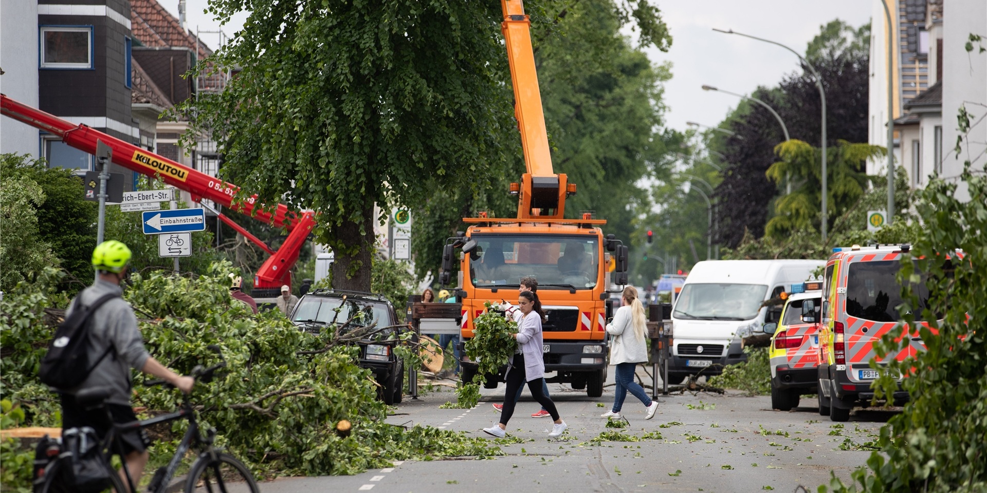Anwohner tragen Grünabfälle und Baumreste an den Straßenrand.