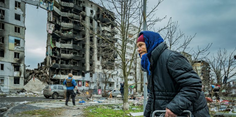 Eine alte Frau geht in der Nähe eines Gebäudes vorbei, das in Folge russischer Angriffe zerstört wurde.
