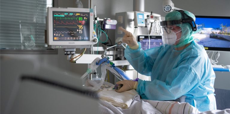 Eine Intensiv-Pflegerin versorgt einen schwer an Corona erkrankten Patienten auf einer Intensivstation (Symbolbild). Auch der Märkische Kreis reduziert seine tägliche Berichterstattung über Fallzahlen.