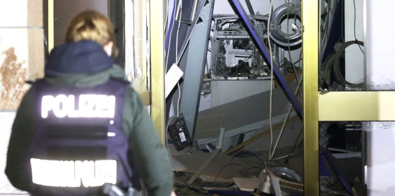 Eine Polizeibeamtin steht vor einem gesprengten Geldautomaten.