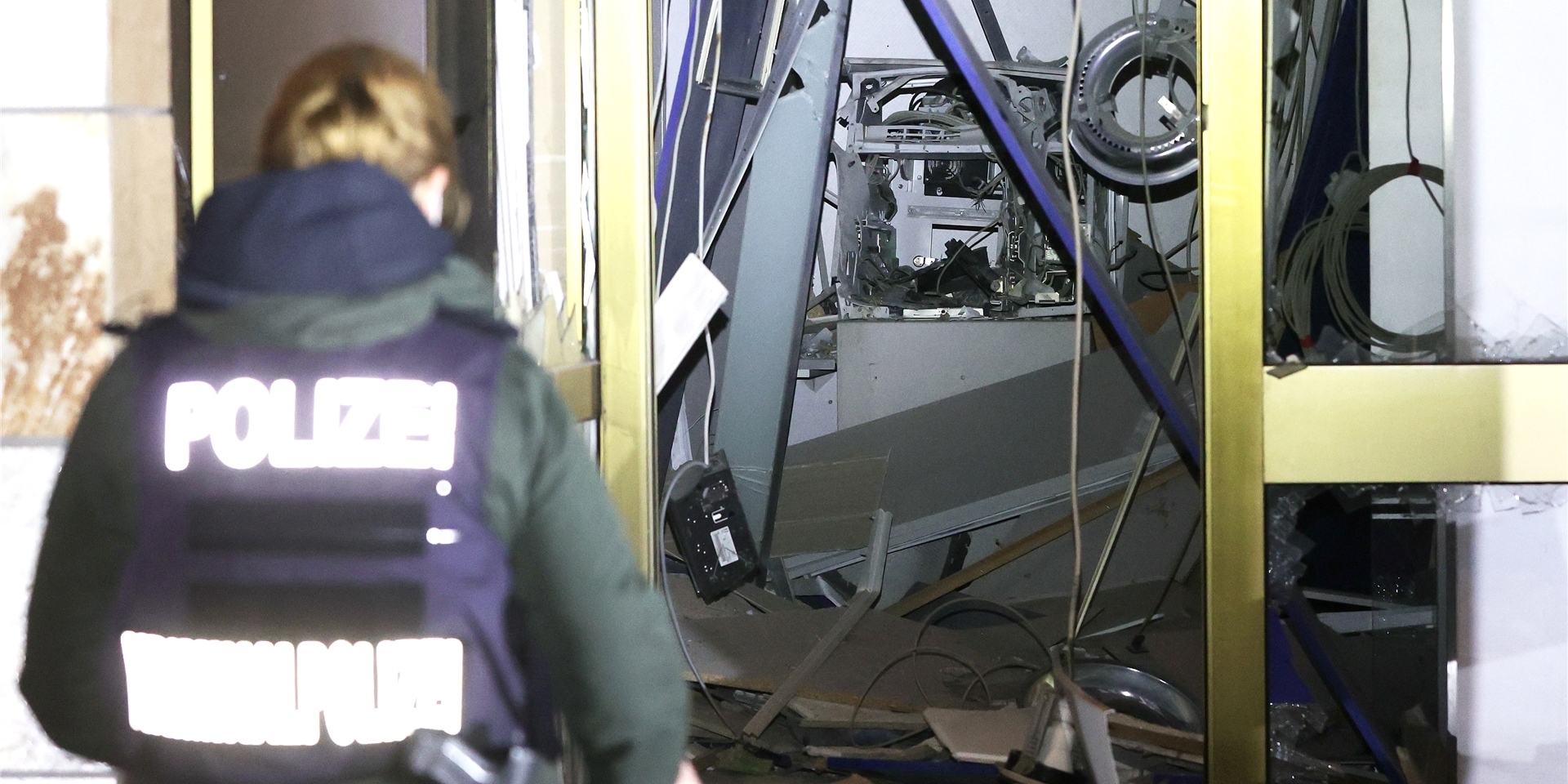 Eine Polizeibeamtin steht vor einem gesprengten Geldautomaten.