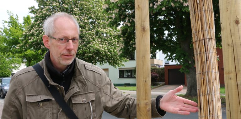 Karsten Harrach an einem jungen Baum am Sesekedamm. Er zeigt eine Bastmanschette, die einen Feldahorn besser vor der Austrocknung schützt. In diesem Frühjahr konnte die Stadt Kamen keine Bäume nachpflanzen.