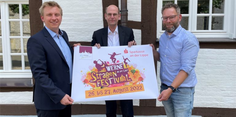 Drei Männer halten ein Plakat