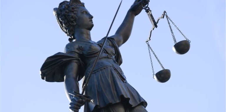 Eine Statue der Justitia steht unter freiem Himmel.