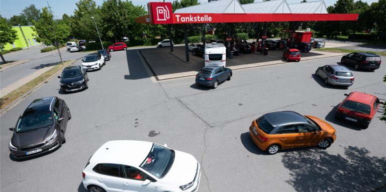 Zahlreiche Autos stehen vor einer Tankstelle.
