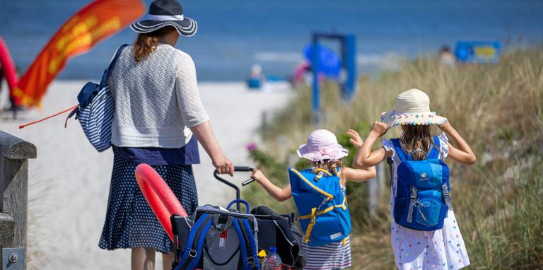 Eine Familie geht an den Ostseestrand in der Nähe der Seebrücke.