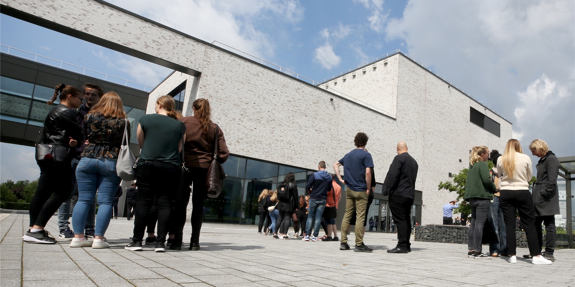 Studierende und Lehrende der Hochschule Hamm stehen trauernd vor dem Hörsaalgebäude der Hochschule.