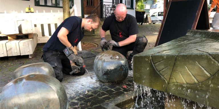 Kastanienreparatur am plätschernden Brunnen: Kunstschmied Martin Bandl (r.) und sein Mitarbeiter bauten eine der Bronzefrüchte ab, um sie zu restaurieren.